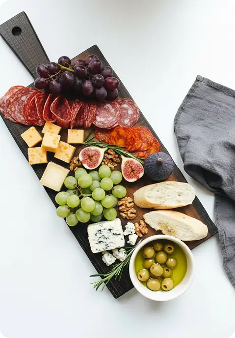worst, druiven, kaasjes, brood, vijgen, olijven en olie op een houten plank