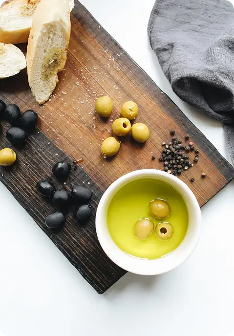Olijfjes, brood en olie op een houten plank