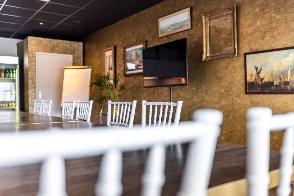 gouden wand, tv, stoelen en tafels in blok opstelling in vergaderlocatie